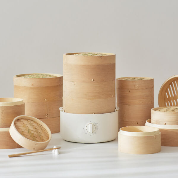 Set of bamboo steamers and a white appliance on a light gray background
