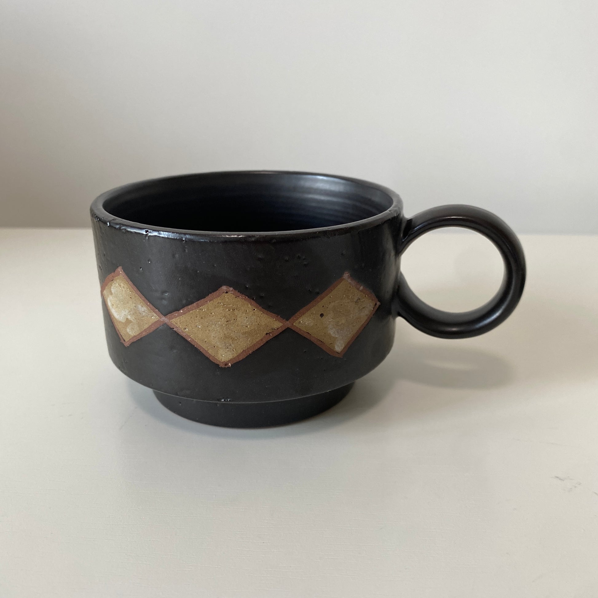 Black ceramic mug with geometric patterns on a white background