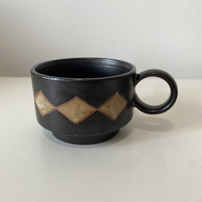 Black ceramic mug with geometric patterns on a white background