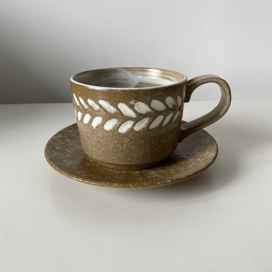 Ceramic cup and saucer with decorative pattern on a white background